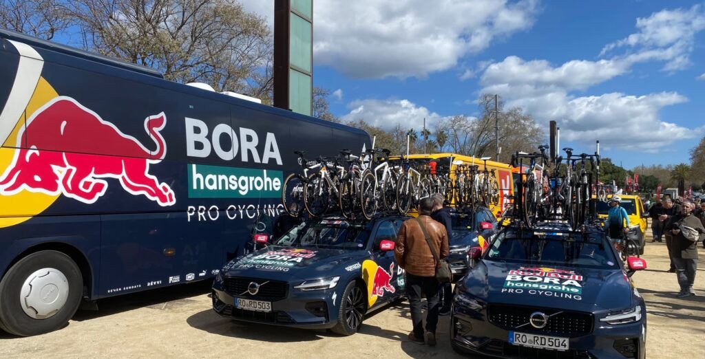 Autobús y coches de carrera del equipo RedBull-Bora en la salida de la etapa 4 de La Volta